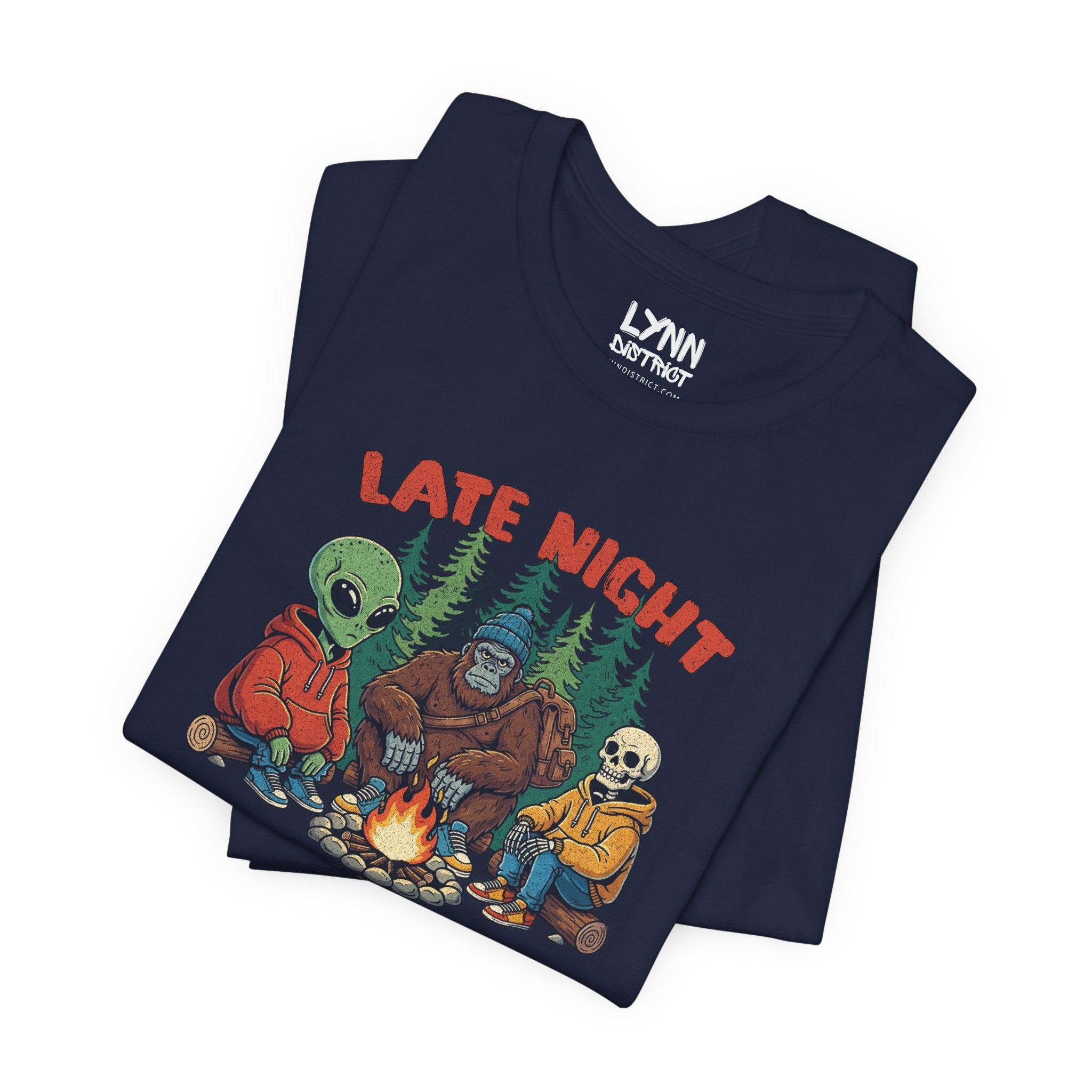Folded navy blue t-shirt with 'Late Night' graphic design featuring alien, bear, and skeleton around a campfire.